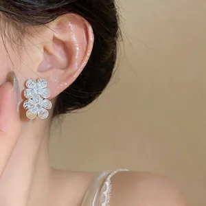 Close-up of elegant silver flower stud earrings with sparkling zircons on a model's ear