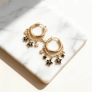 Close-up of gold hoop earrings with dangling stars and gothic cross detail in black enamel.