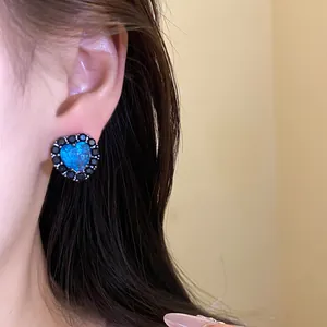 Detailed close-up of elegant blue heart stud earring with black zirconia border.