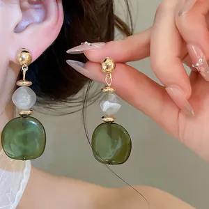 Primer plano de pendientes de resina jaspeada estilo neo-chino con cuentas verdes