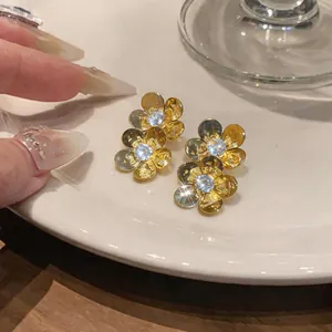 Close-up of elegant gold-colored double flower stud earrings with sparkling zircons
