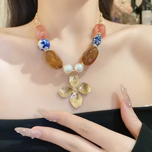 Close-up of vintage beaded necklace with gold flower pendant and ceramic beads
