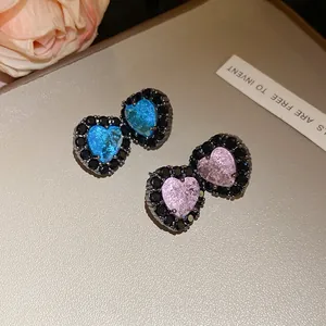 Detailed close-up of heart-shaped zircon stud earrings with elegant black gemstone borders.