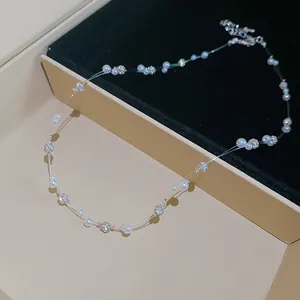 Close-up detail of delicate pearl and rhinestone bead necklace on transparent cord