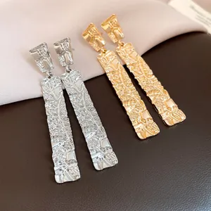Macro detail of silver and gold rectangular earrings with a wrinkled texture finish