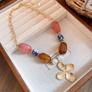 Detailed view of a vintage beaded necklace with a golden flower pendant in a jewelry tray.