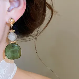 Primer plano de pendientes de resina marbreada verde en una modelo asiática para un look