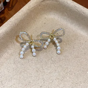 Macro view of elegant bow-shaped pearl stud earrings with 14k gold plating and crystals