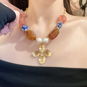 Detailed view of vintage beaded necklace featuring gold flower pendant and ceramic pearls