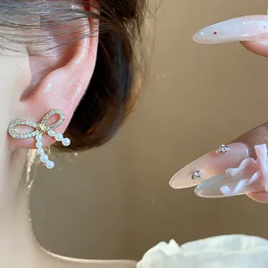 Detailed close-up showing elegant bow-shaped earrings with pearls and crystals on ear