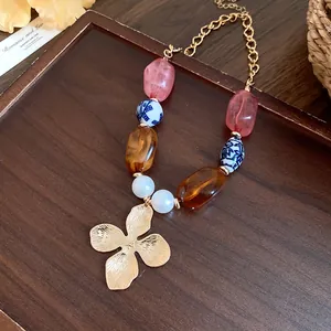 Detailed view of a vintage ceramic pearl beaded necklace with a gold flower pendant