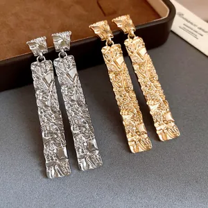 Detail of luxury rectangular earrings with unique crumpled texture in gold and silver