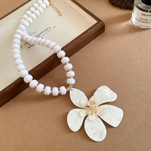 Detailed view of vintage French white beaded necklace with large resin flower pendant.