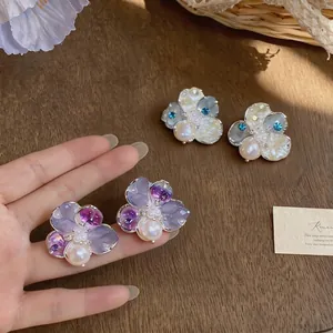 Sweet floral stud earrings with zircon and pearls on a natural wood background