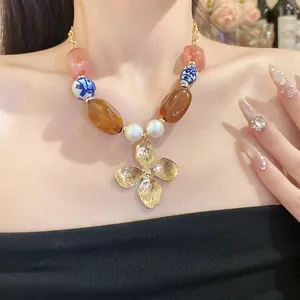 Close-up of retro floral pendant necklace featuring ceramic beads and pearls on a model