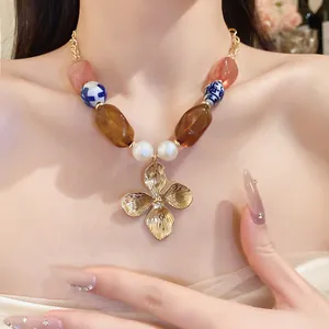 Close-up view of vintage beaded necklace featuring gold flower pendant and ceramic beads