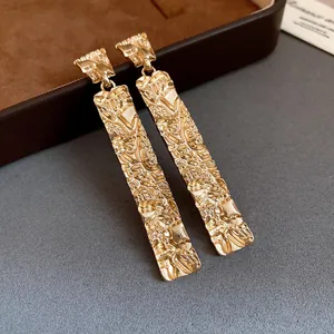 Detailed macro shot of textured gold rectangular drop earrings with crinkled finish
