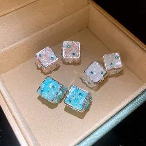 Orecchini a perno quadrati con intarsio di conchiglie e strass blu in una scatola