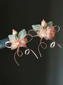Detailed macro view of pink fabric flower hair clips with curled ribbons and ruler for scale
