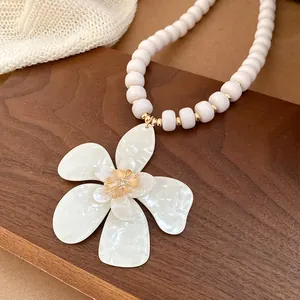 Detail view of a French vintage necklace with white beads and a rhinestone flower pendant