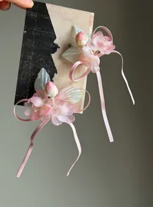 Detail shot of pink fabric flower hair clips with long ribbons on a display card