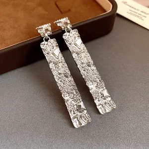 Close-up detail of stylish silver rectangular earrings with unique crinkled texture