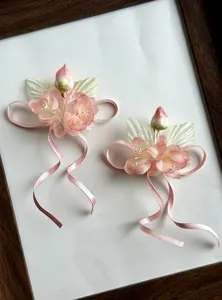 Elegant close-up of pink fabric flower hair clips featuring long satin ribbon streamers