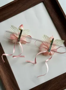 Detail view of pink floral ribbon hair clips with duckbill clips measured by a scale ruler