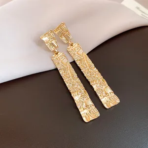 Macro view of gold textured rectangular drop earrings for a chic minimalist look