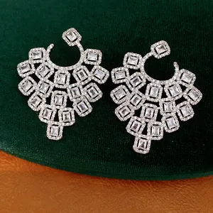 Detailed macro shot of heavy geometric earrings inlaid with clear sparkling zirconia stones.