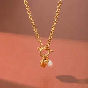 Detail of a stainless steel necklace featuring a heart pendant and a freshwater pearl accent