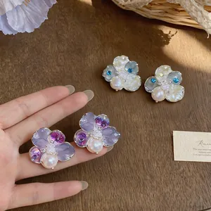 Detailed view of sweet floral stud earrings with pearls and crystals on silver needles