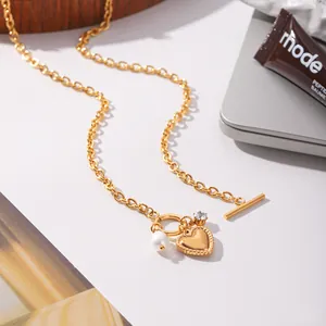 Close-up detail of a gold-plated stainless steel necklace with a heart pendant and pearl.