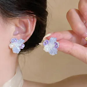Detailed view of sweet floral earrings with elegant pearls and zircons worn on ear