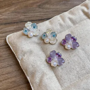 Close-up of floral stud earrings with pearls and colorful petals on a display pad