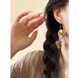 Detailed close-up view of vintage ethnic-style pinecone fruit tassel earring on model