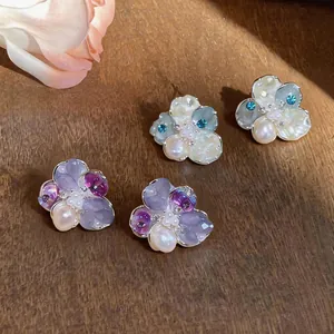 Macro detail of elegant flower stud earrings with synthetic pearls and zircons on wood background