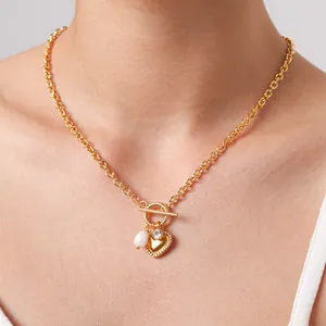 Close-up of gold heart pendant necklace with freshwater pearl on a model.