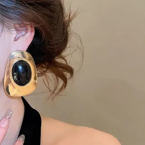 Vintage gold chunky oval earrings with black resin center worn by a female model in profile