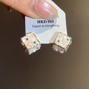 Dettaglio orecchini a lobo cubici in conchiglia con cristalli blu e ago d'argento