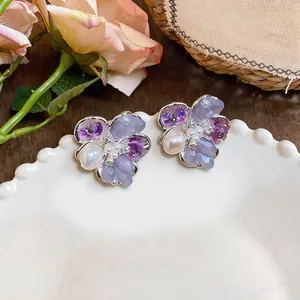 Close-up of sweet purple floral stud earrings with pearls and crystals
