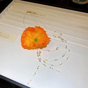 Detail of a sweet orange flower necklace with clear beads and gold tassels