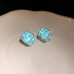 Dettaglio di orecchini a cubo con trama in conchiglia blu e piccoli cristalli