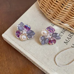 Exquisite detail view of purple floral stud earrings with imitation pearls and stones.