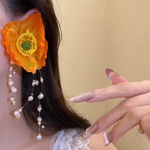 Close-up detail of an orange silk poppy flower earring with elegant white pearl tassels