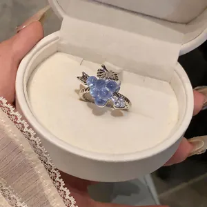 Detail view of a silver grape ring with blue beads and a heart-shaped zircon in a box.