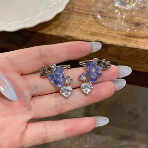 Close-up detail of exquisite grape-shaped ear cuffs with heart zircon held on a hand