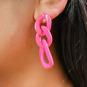 Detailed view of vibrant pink acrylic chain link earrings worn on a person's ear