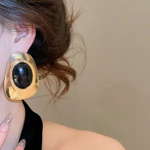 Detail of vintage resin oval stud earring in gold and black finish shown on model ear