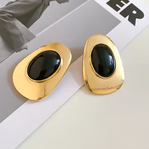 Macro view of vintage gold-tone oval statement earrings featuring a glossy black resin center
